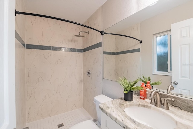 bathroom featuring toilet, vanity, and tiled shower