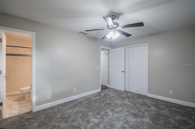 unfurnished bedroom with ceiling fan, ensuite bathroom, a closet, and dark colored carpet