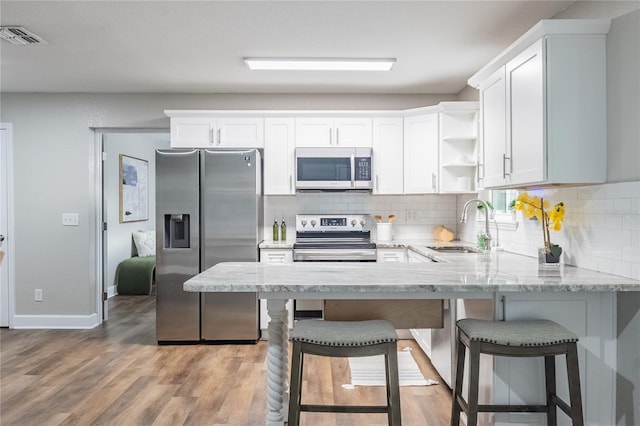 kitchen featuring tasteful backsplash, hardwood / wood-style floors, sink, white cabinetry, and appliances with stainless steel finishes