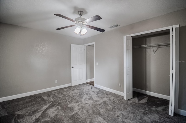 unfurnished bedroom with ceiling fan, a closet, and dark carpet