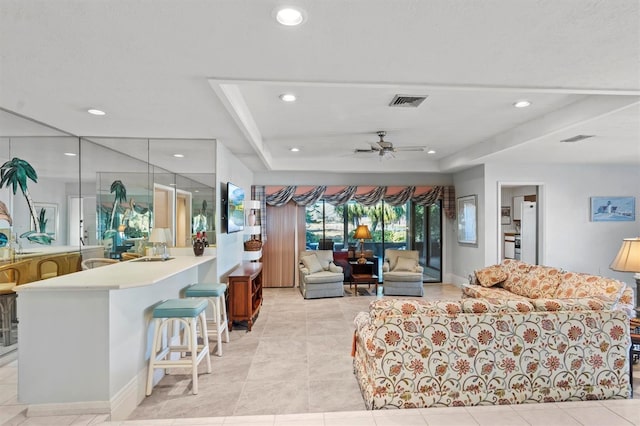 tiled living room with a tray ceiling and ceiling fan