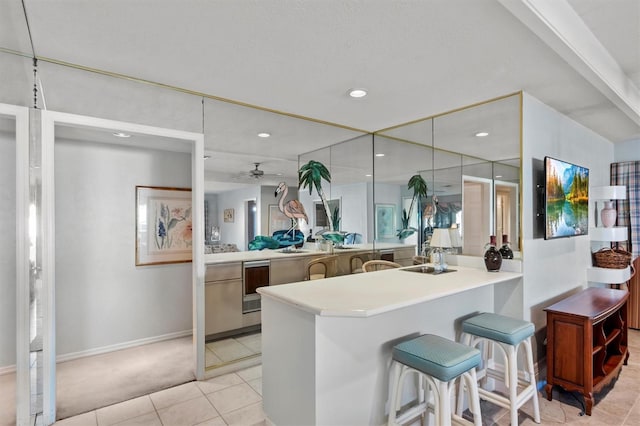 kitchen featuring ceiling fan, wine cooler, kitchen peninsula, a breakfast bar, and light tile patterned floors