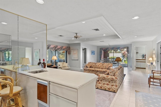 kitchen featuring light tile patterned flooring, ceiling fan, a kitchen island with sink, and sink