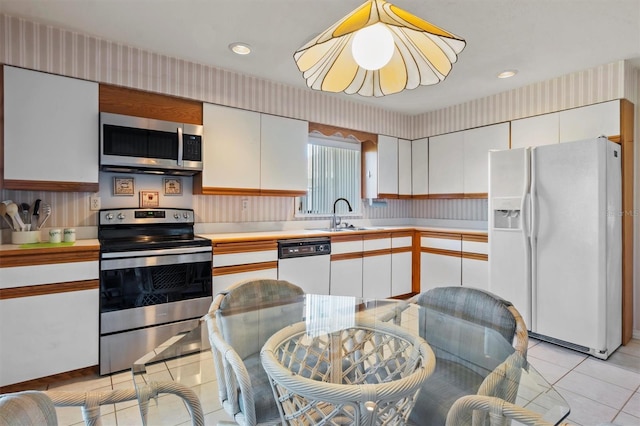 kitchen with light tile patterned floors, stainless steel appliances, white cabinetry, and sink