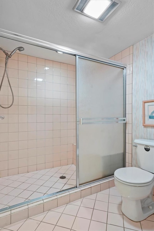 bathroom featuring tile patterned flooring, an enclosed shower, and a textured ceiling