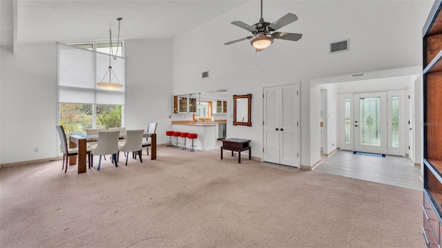 carpeted dining room featuring high vaulted ceiling and ceiling fan