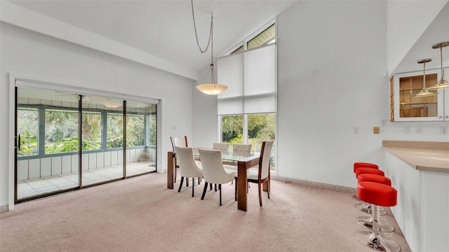 carpeted dining room with a healthy amount of sunlight and high vaulted ceiling