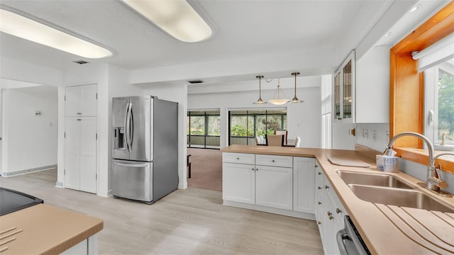 kitchen with pendant lighting, sink, light wood-type flooring, white cabinetry, and stainless steel appliances