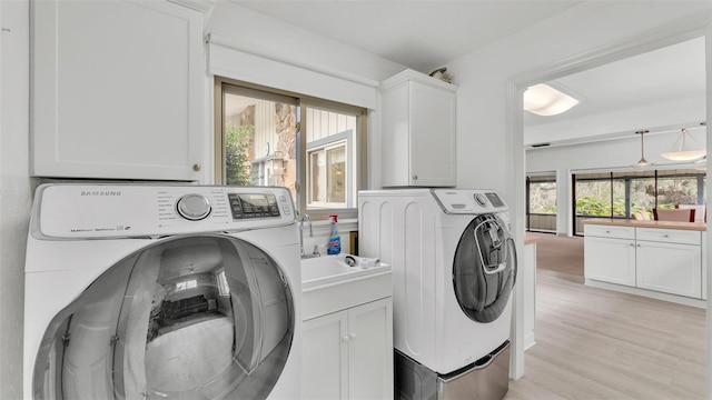 laundry area with cabinets, light hardwood / wood-style flooring, and washer and dryer