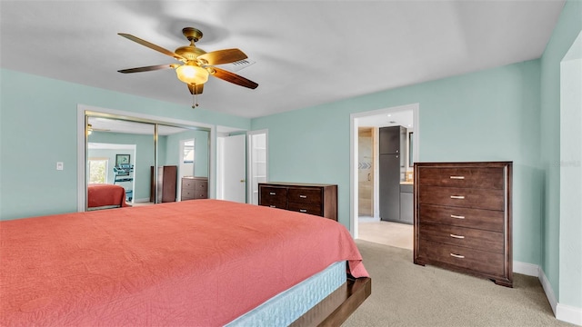 carpeted bedroom with a closet, ensuite bath, ceiling fan, and stainless steel refrigerator