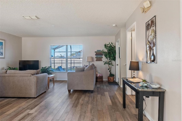 living room with a textured ceiling and dark hardwood / wood-style floors