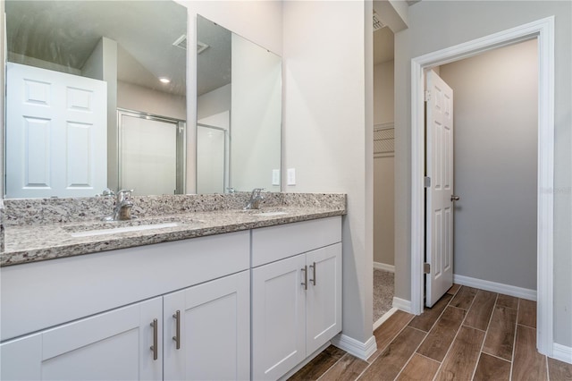 bathroom featuring a shower with door and vanity