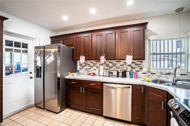 kitchen with sink, stainless steel appliances, backsplash, decorative light fixtures, and light tile patterned flooring