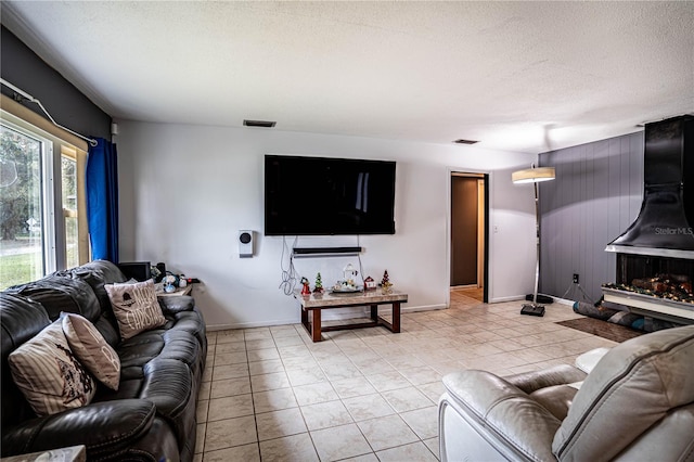 living room featuring a textured ceiling, light tile patterned floors, and a fireplace