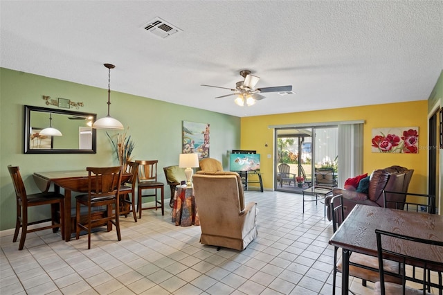 living area featuring light tile patterned flooring, a ceiling fan, a textured ceiling, baseboards, and visible vents