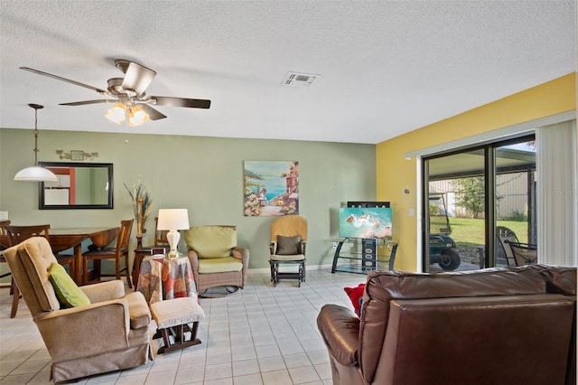 living room with a textured ceiling, visible vents, a ceiling fan, and light tile patterned floors