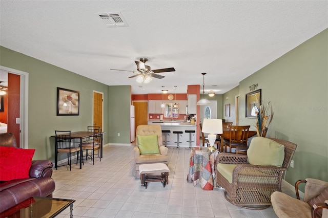 living room with baseboards, ceiling fan, visible vents, and light tile patterned floors