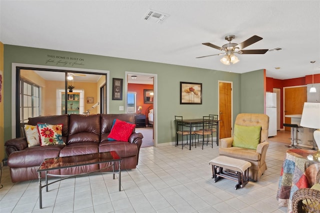 tiled living room featuring baseboards, visible vents, and a ceiling fan