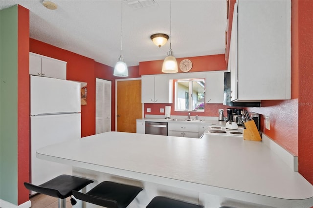 kitchen with light countertops, a peninsula, white appliances, a sink, and hanging light fixtures