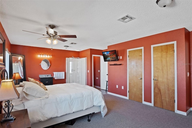 carpeted bedroom featuring baseboards, visible vents, two closets, and a textured ceiling