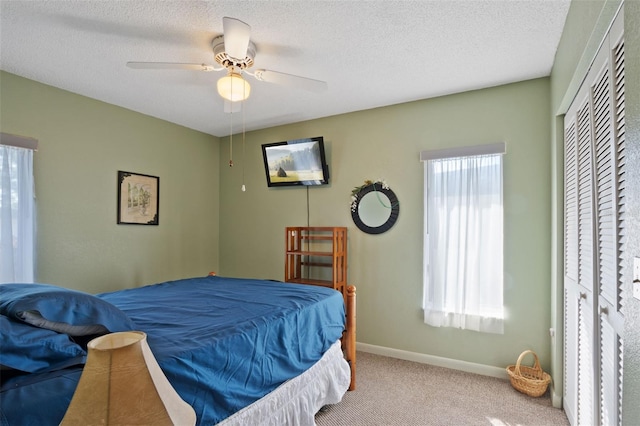 carpeted bedroom with baseboards, a textured ceiling, and ceiling fan