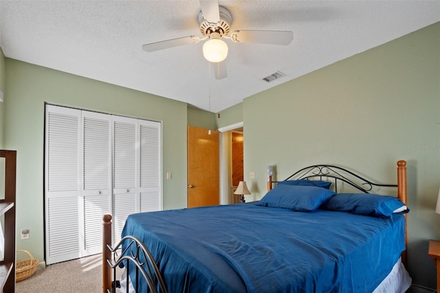 carpeted bedroom with a textured ceiling, a closet, ceiling fan, and visible vents