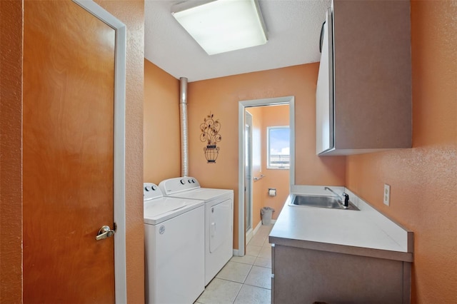 laundry room featuring light tile patterned floors, a sink, cabinet space, and separate washer and dryer
