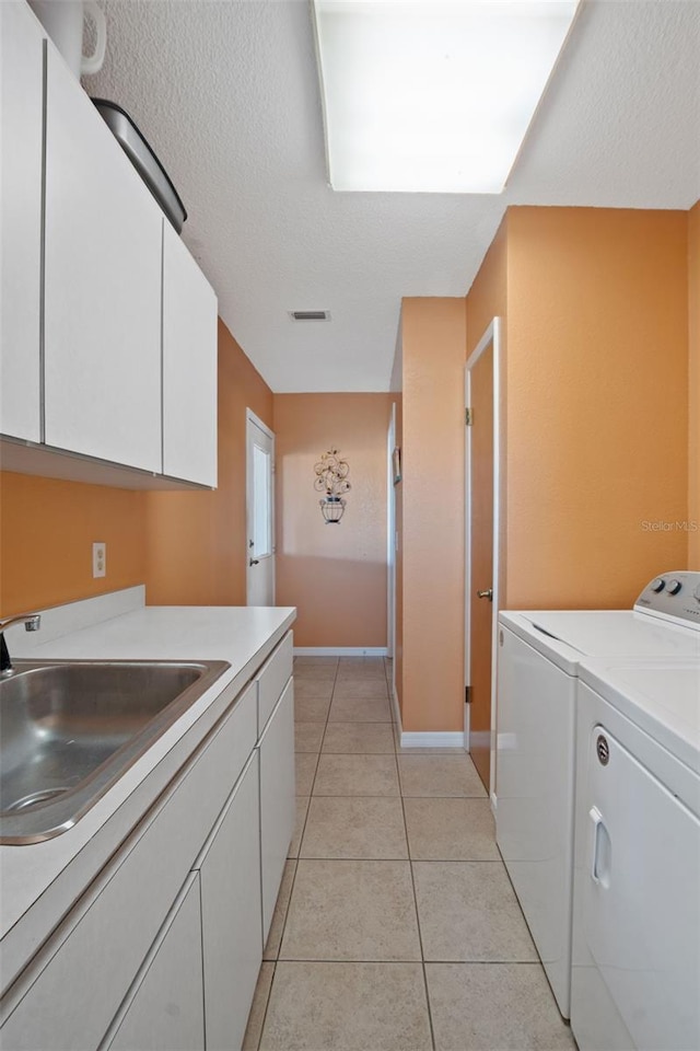 laundry room featuring washing machine and clothes dryer, a sink, light tile patterned flooring, visible vents, and cabinet space