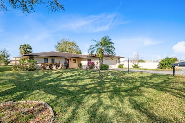 ranch-style home with stucco siding, fence, driveway, a front yard, and a garage