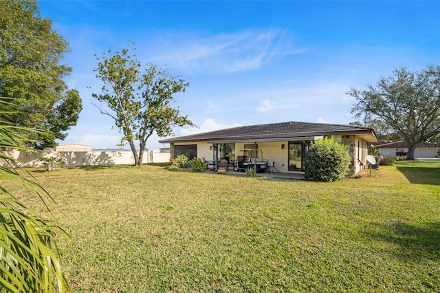 back of house with a patio, stucco siding, fence, and a yard
