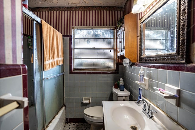 full bathroom with vanity, combined bath / shower with glass door, tile patterned flooring, toilet, and tile walls