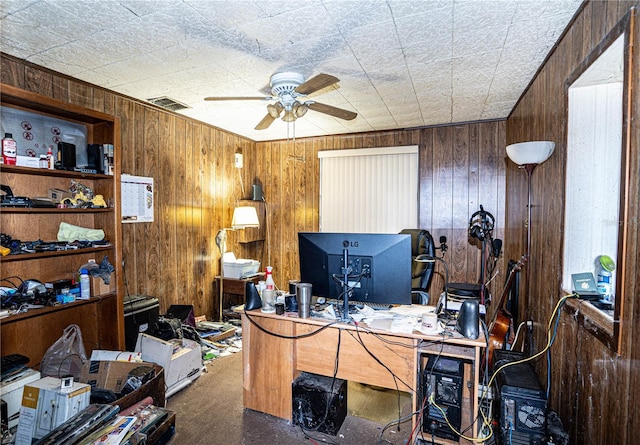 home office featuring carpet flooring, ceiling fan, and wooden walls