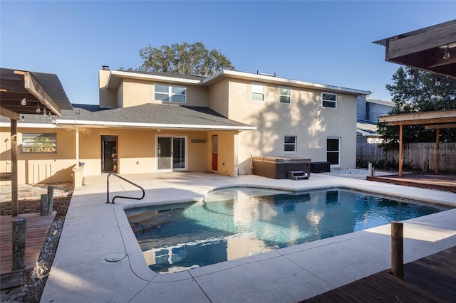 back of property featuring a swimming pool with hot tub and a patio area