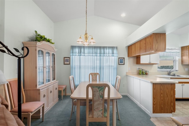 dining room featuring light carpet, sink, a chandelier, and vaulted ceiling