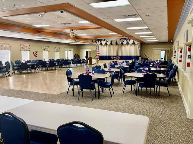 carpeted dining space featuring ceiling fan and a drop ceiling