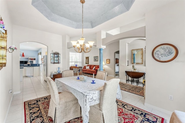 tiled dining space with a chandelier and a raised ceiling