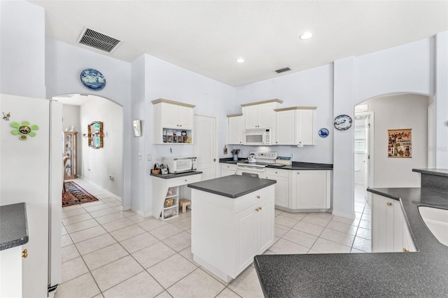 kitchen with light tile patterned floors, white cabinets, white appliances, and a kitchen island