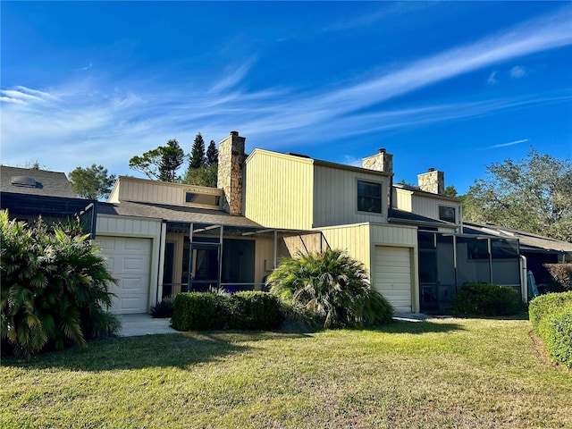 back of house featuring a lawn, a sunroom, and a garage