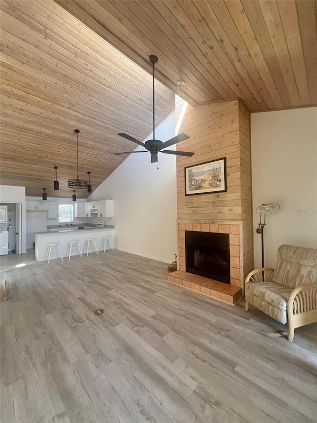 unfurnished living room featuring a fireplace, wooden ceiling, vaulted ceiling, and light hardwood / wood-style flooring