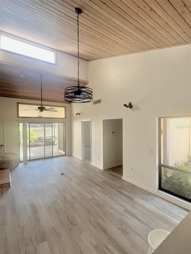 unfurnished living room featuring a towering ceiling, light hardwood / wood-style floors, ceiling fan, and wood ceiling