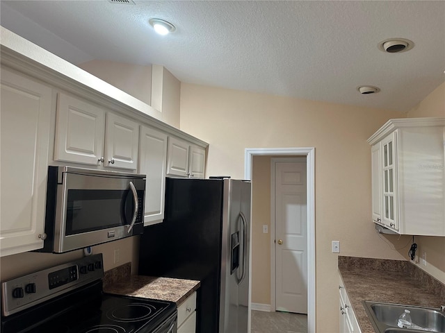 kitchen with white cabinets, sink, light tile patterned floors, a textured ceiling, and stainless steel appliances