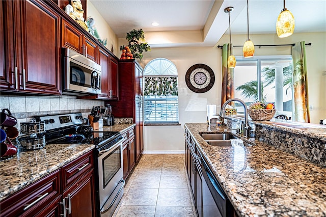 kitchen featuring appliances with stainless steel finishes, dark stone counters, sink, pendant lighting, and light tile patterned flooring