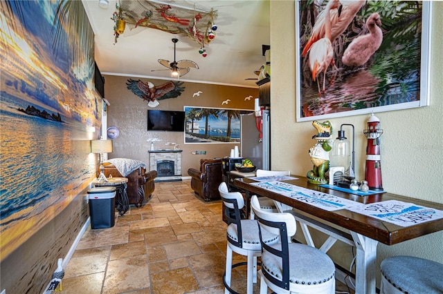 dining area with a fireplace, ceiling fan, and crown molding