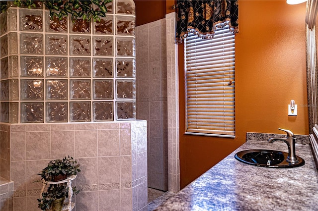 bathroom with a tile shower and vanity