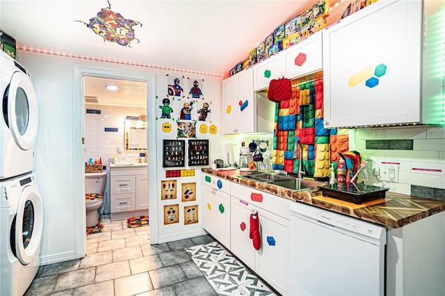 kitchen with dishwasher, sink, tasteful backsplash, stacked washer / drying machine, and white cabinetry