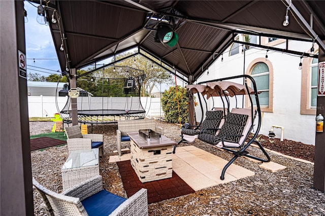 view of patio / terrace with a gazebo, a trampoline, and an outdoor fire pit