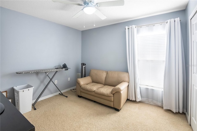 living area with light carpet and ceiling fan