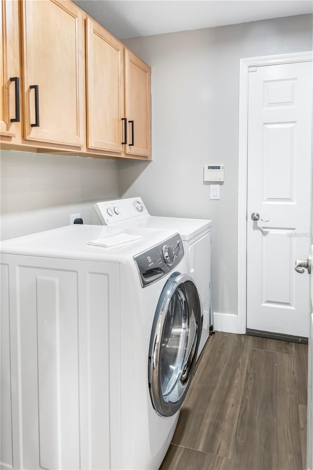 clothes washing area with cabinets, separate washer and dryer, and dark wood-type flooring