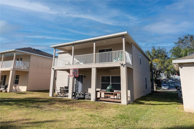 back of house featuring a lawn, a patio area, and a balcony