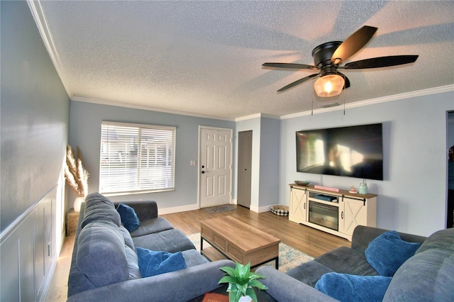 living room with hardwood / wood-style flooring, ceiling fan, and ornamental molding